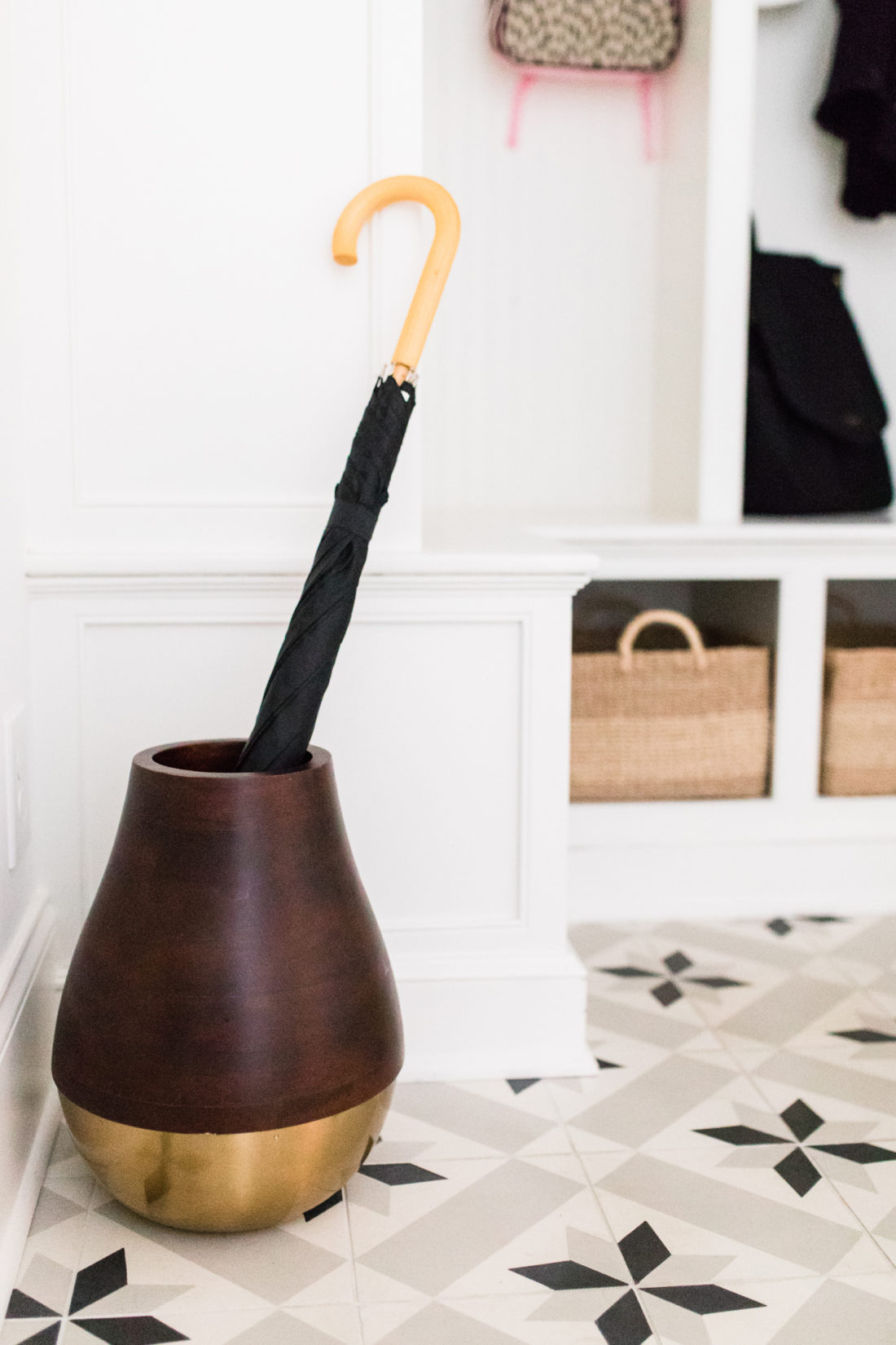 A wood and brass umbrella stand in the black and white tiled mudroom in Eva Amurri Martino's Connecticut home