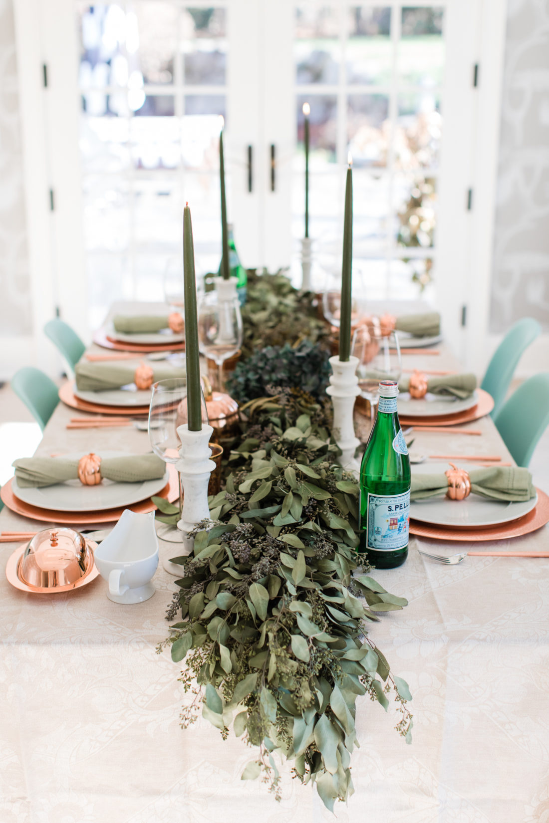 A eucaluptus garland, marble candlesticks with green candles, and a green and copper color scheme add style to Eva Amurri Martino's thanksgiving table