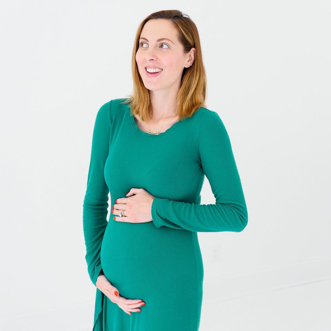 Eva Amurri Martino of the Happily Eva After blog cradling her thirty three week baby bump wearing a green long sleeved maternity maxi dress 