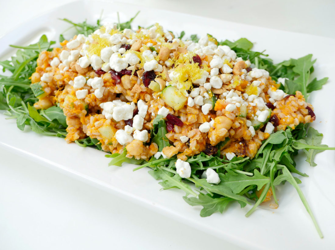 Happily Eva After Autumn Farro Salad with Sweet Potato, Cucumber, Chickpeas, cranberries, goat cheese, cashews, arugula, and lemon zest phtographed in a marble kitchen with a blue shibori dyed tea towel and sunflowers