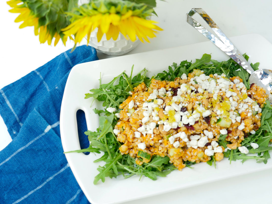 Happily Eva After Autumn Farro Salad with Sweet Potato, Cucumber, Chickpeas, cranberries, goat cheese, cashews, arugula, and lemon zest phtographed in a marble kitchen with a blue shibori dyed tea towel and sunflowers