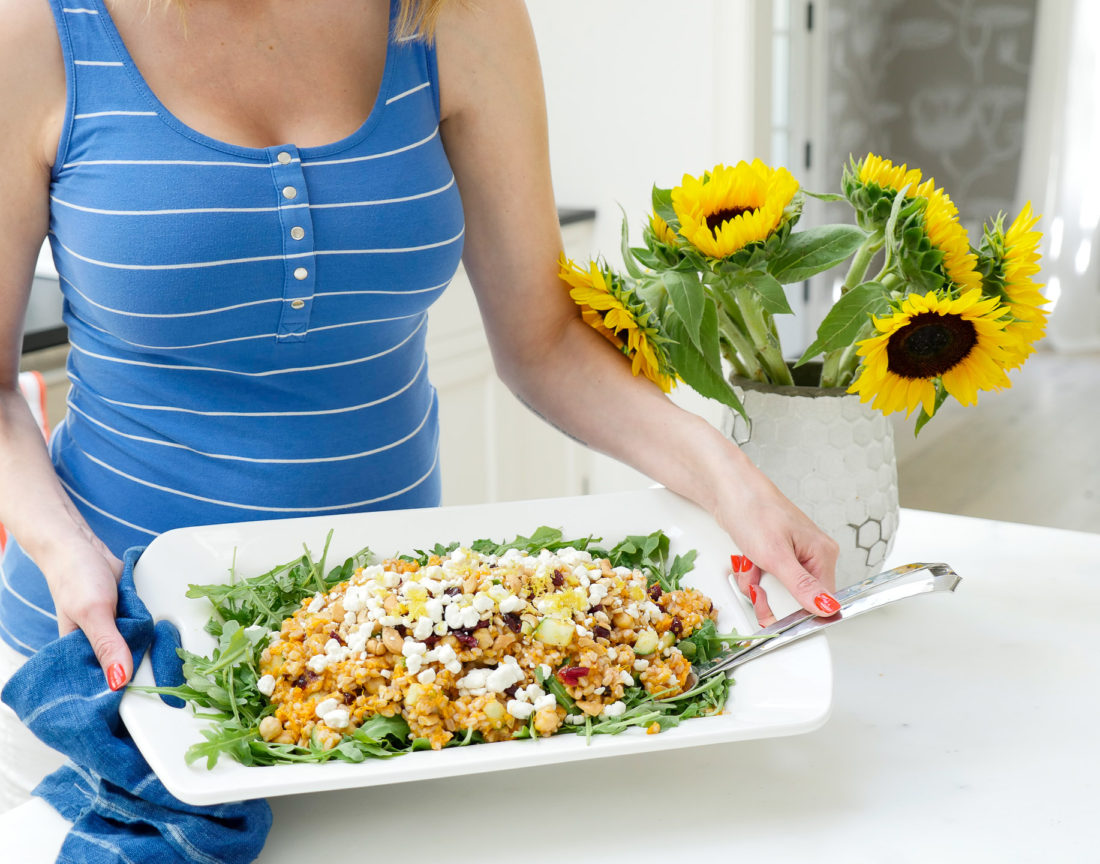 Happily Eva After Autumn Farro Salad with Sweet Potato, Cucumber, Chickpeas, cranberries, goat cheese, cashews, arugula, and lemon zest phtographed in a marble kitchen with a blue shibori dyed tea towel and sunflowers