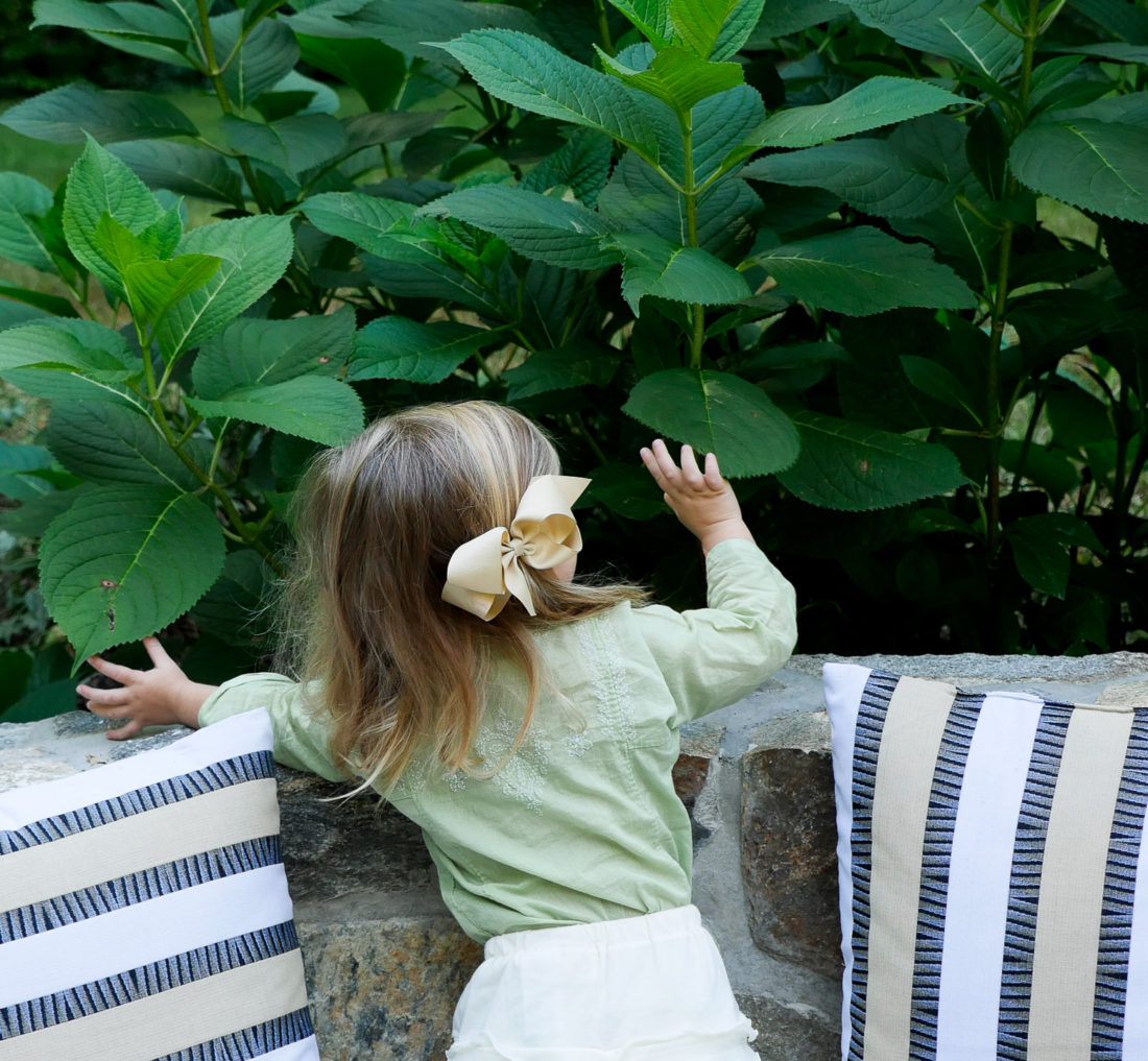 Photo of Marlowe Martino on Happily Eva After blog wearing a green tunic and white ruffled shorts with a beige bow in her hair