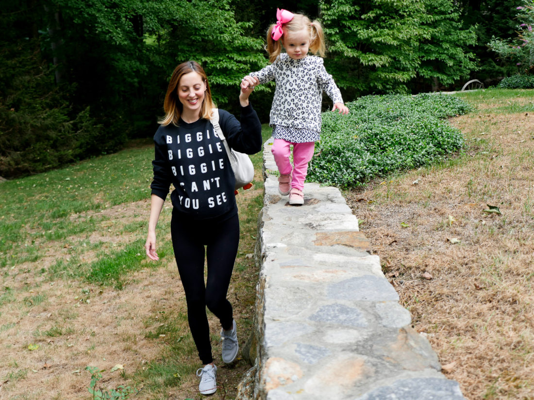 Eva Amurri Martino of blog Happily Eva After wearing black leggings and a "Biggie Biggie Biggie can't you see" sweatshirt at thirty five weeks pregnant walking with her daughter marlowe wearing DSW adidas shoes