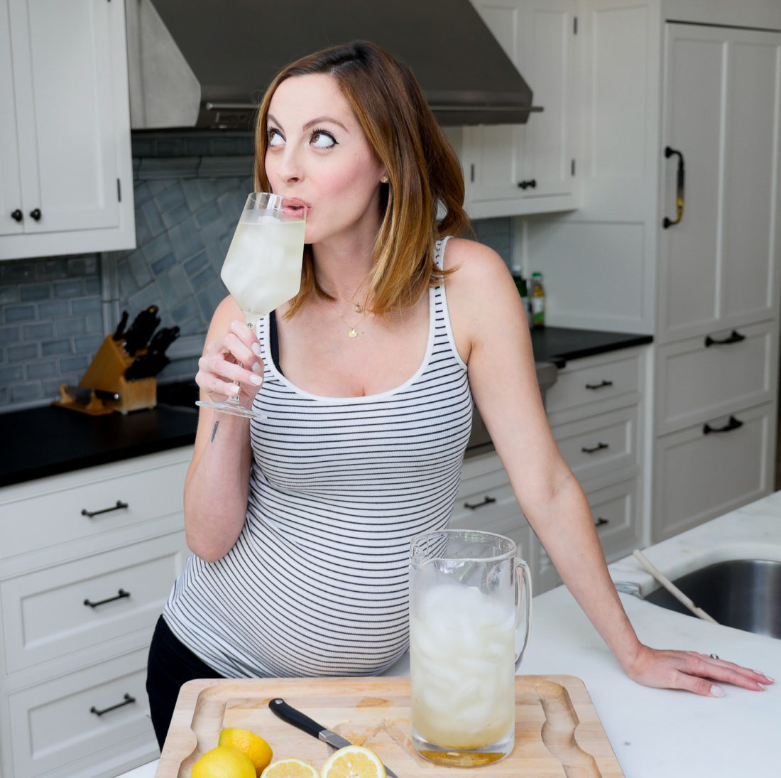 Eva Amurri Martin of lifestyle blog Happily Eva After, drinking a home made Laborade electrolyte drink in her kitchen at 35 weeks pregnant