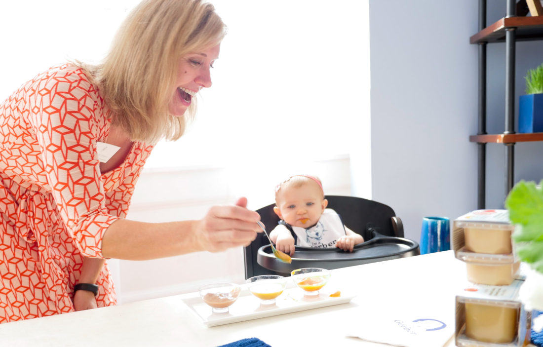 A Gerber representative feeding baby food to a child at the Gerber Babies Event in NYC, as photographed by Eva Amurri Martino of lifestyle and motherhood blog Happily Eva After