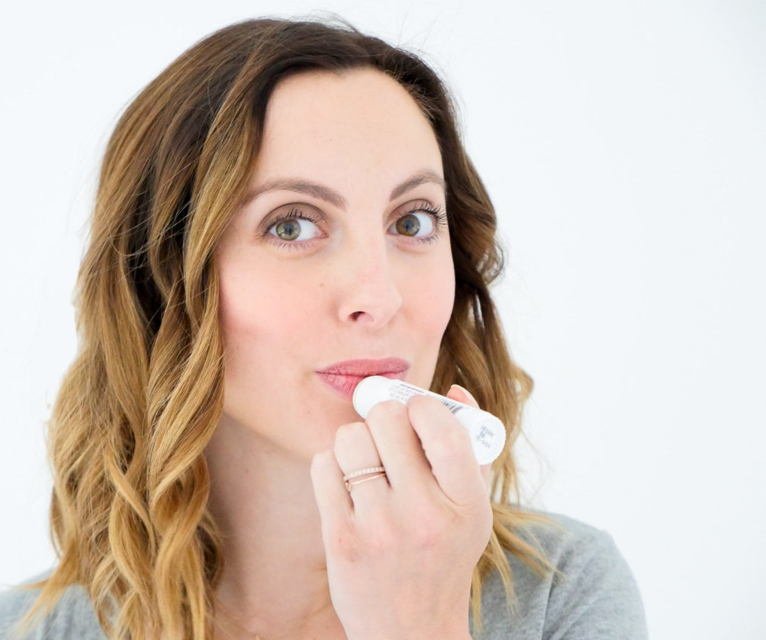Eva Amurri Martino of lifestyle blog Happily Eva After applying repairing balm to her lips as part of her monthly beauty picks for october