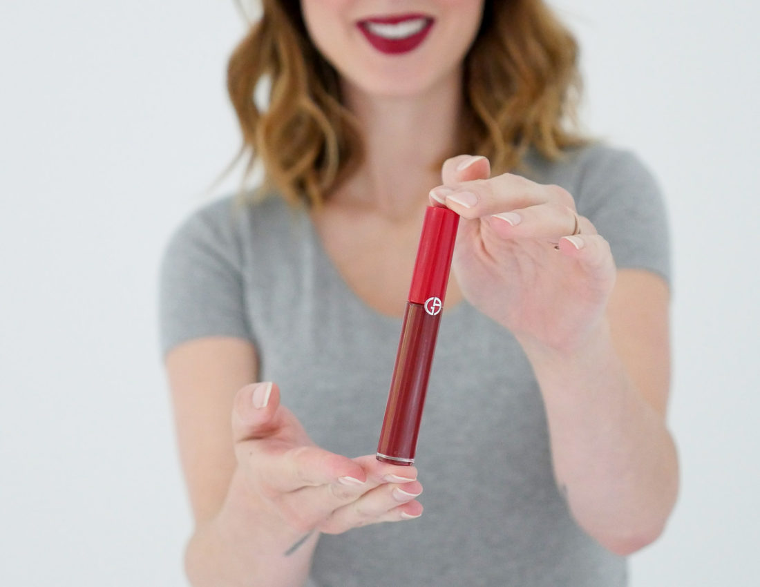 Eva Amurri Martino of lifestyle blog Happily Eva After showing off a red liquid lipstick as part of her monthly beauty picks for october