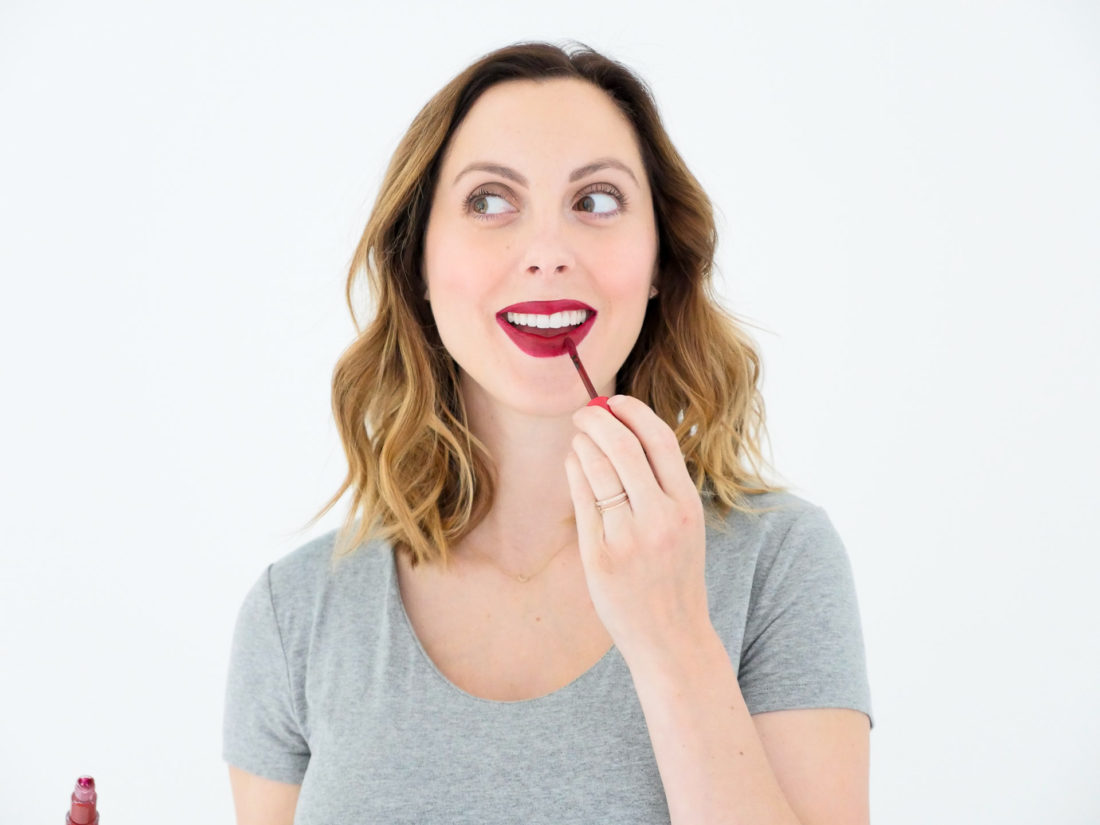 Eva Amurri Martino of lifestyle blog Happily Eva After applying red liquid lipstick as part of her monthly beauty picks for October