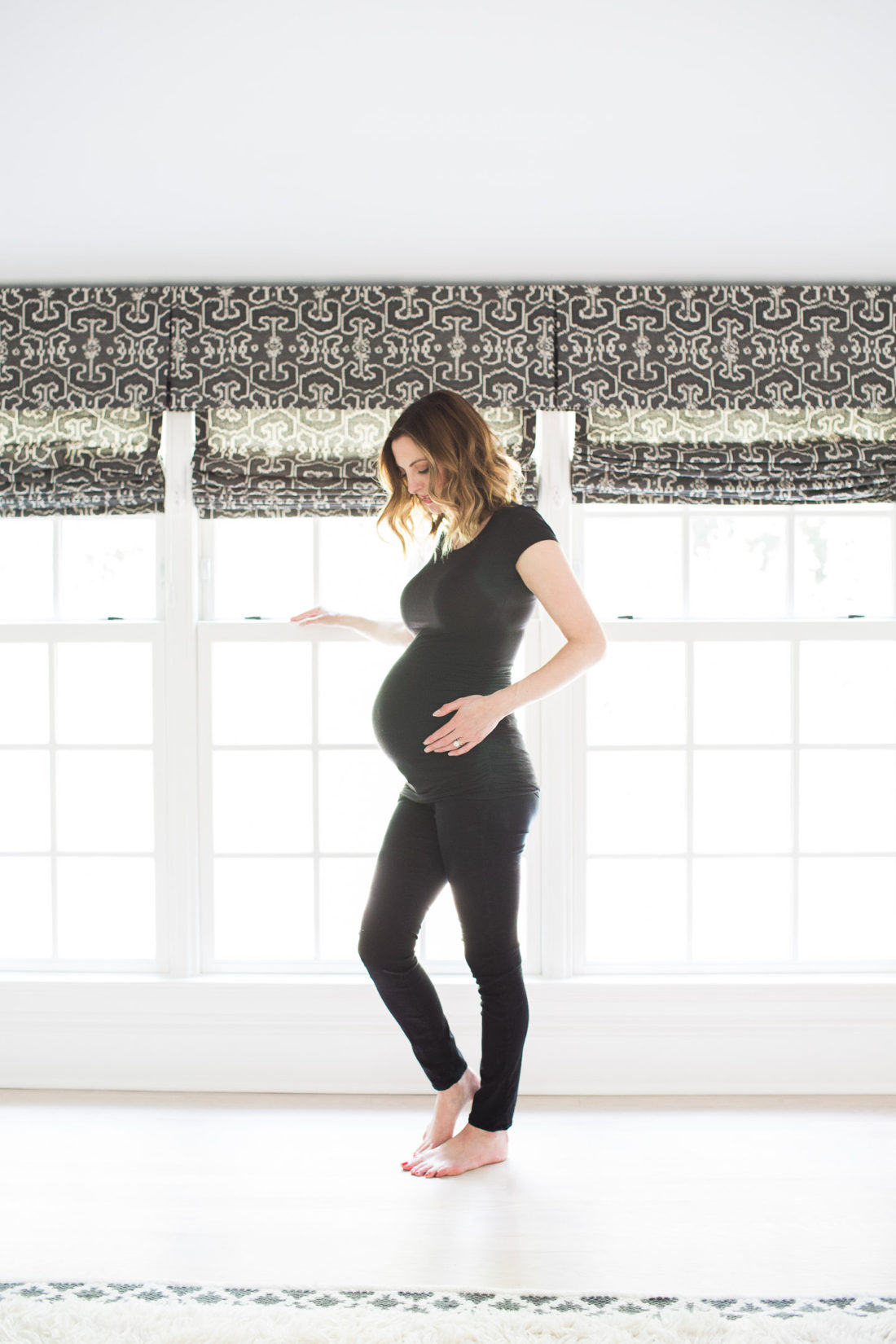 Eva Amurri Martino of lifestyle and motherhood blog Happily Eva After, wearing all black and cradling her baby bump