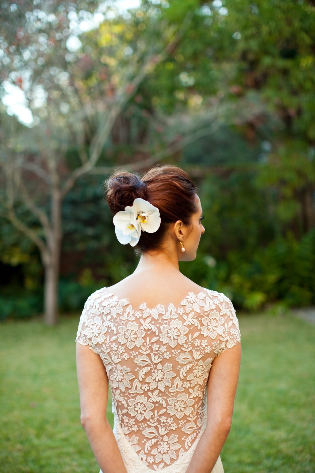 The back detail of Eva Amurri Martino's Lela Rose wedding dress, worn with a high bun hairstyle and two white orchids pinned in the back