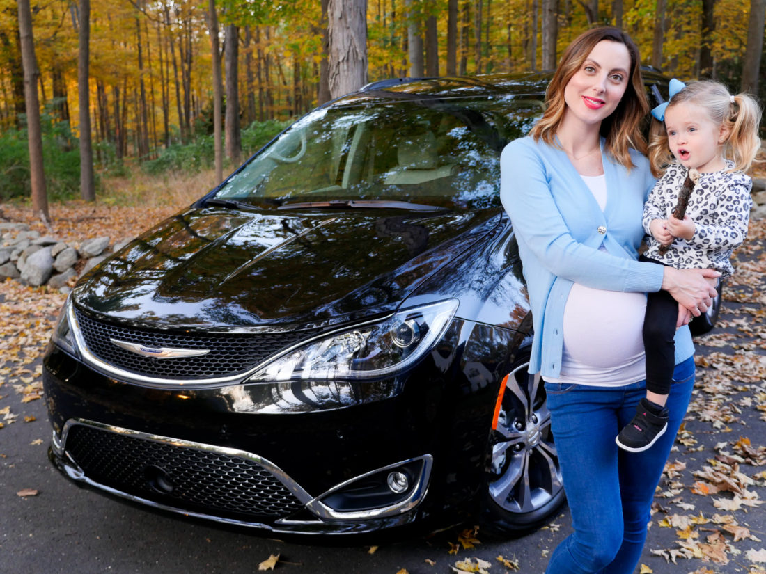 Eva Amurri Martino is pictured at nine months pregant, holding daughter Marlowe in front of her black Chrysler Pacifica