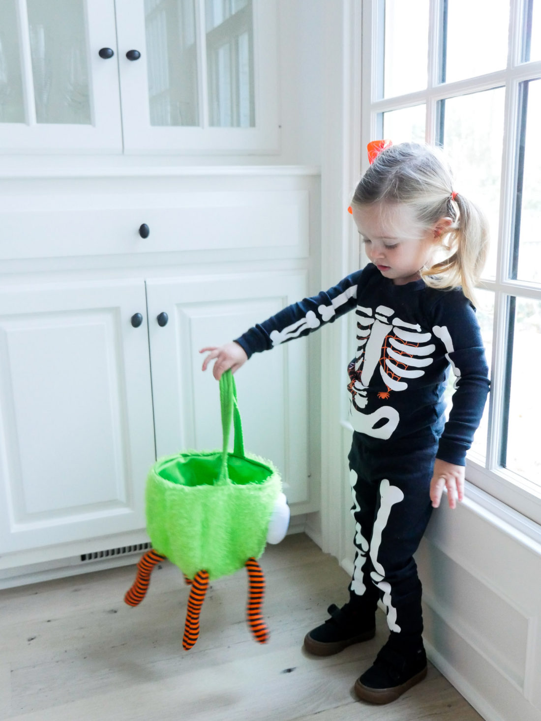 Marlowe Martino dressed up as a skeleton for halloween, holding a green and orange trick or treating bag