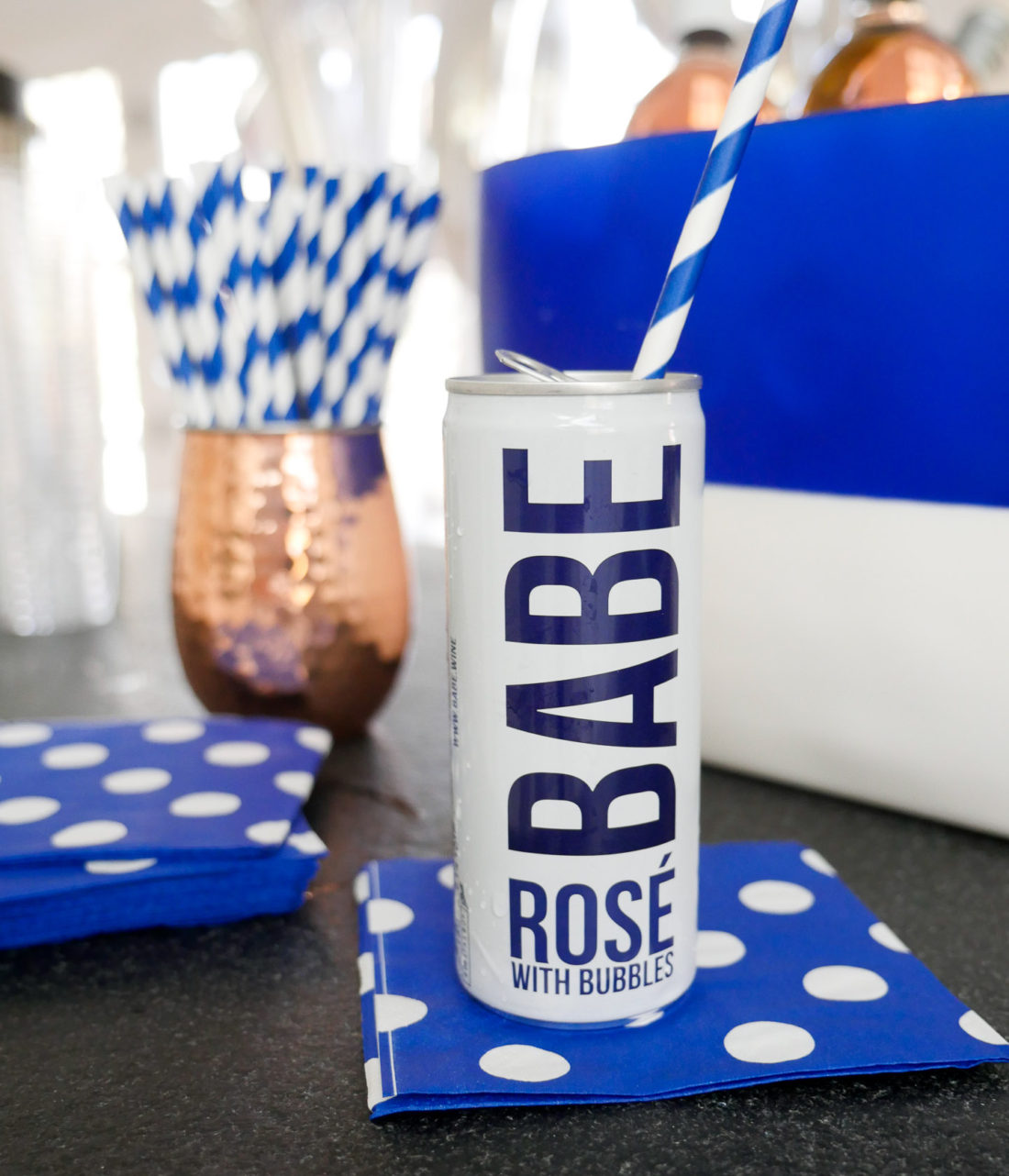 Babe Rose with bubbles pictured on a blue and white polka dot napkin with a blue and white striped straw 
