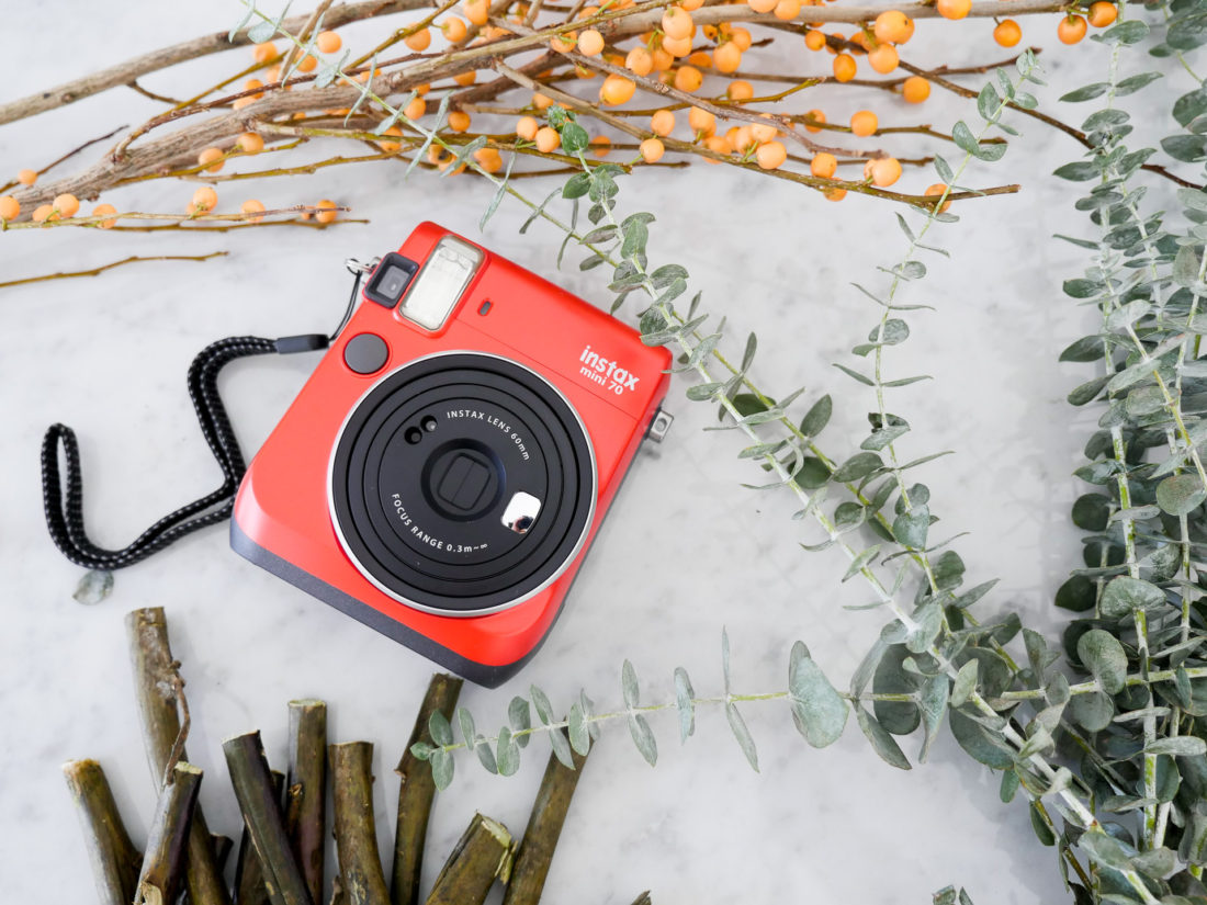 The instax mini 70 camera pictured with the materials to make holiday picture frame place cards for your holiday table, as instructed by lifestyle and motherhood blogger Eva Amurri Martino