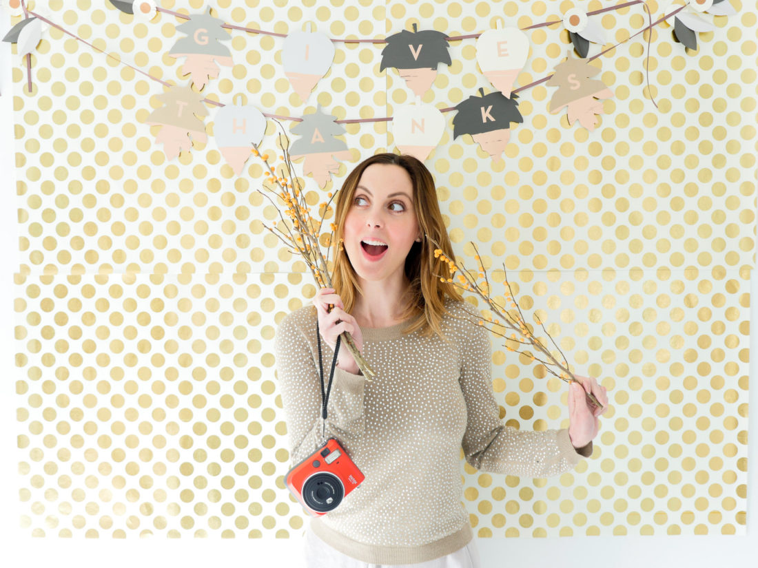 Eva Amurri Martino poses in front of her festive Thanksgiving backdrop as part of her DIY Holiday Photo Place Card settings project with Instax mini 70