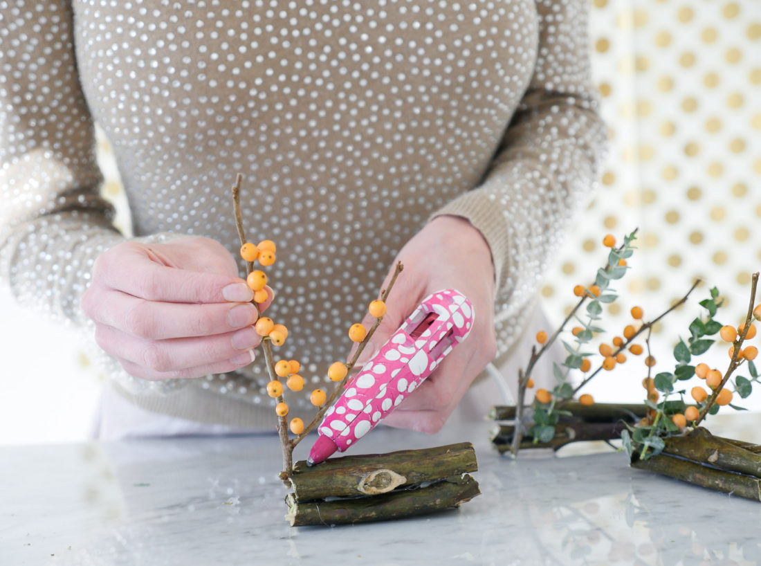 Eva Amurri Martino wearing a tan rhinestock embellished sweater, constructing her DIY Holiday Photo Frame Placecards using the Instax mini 70