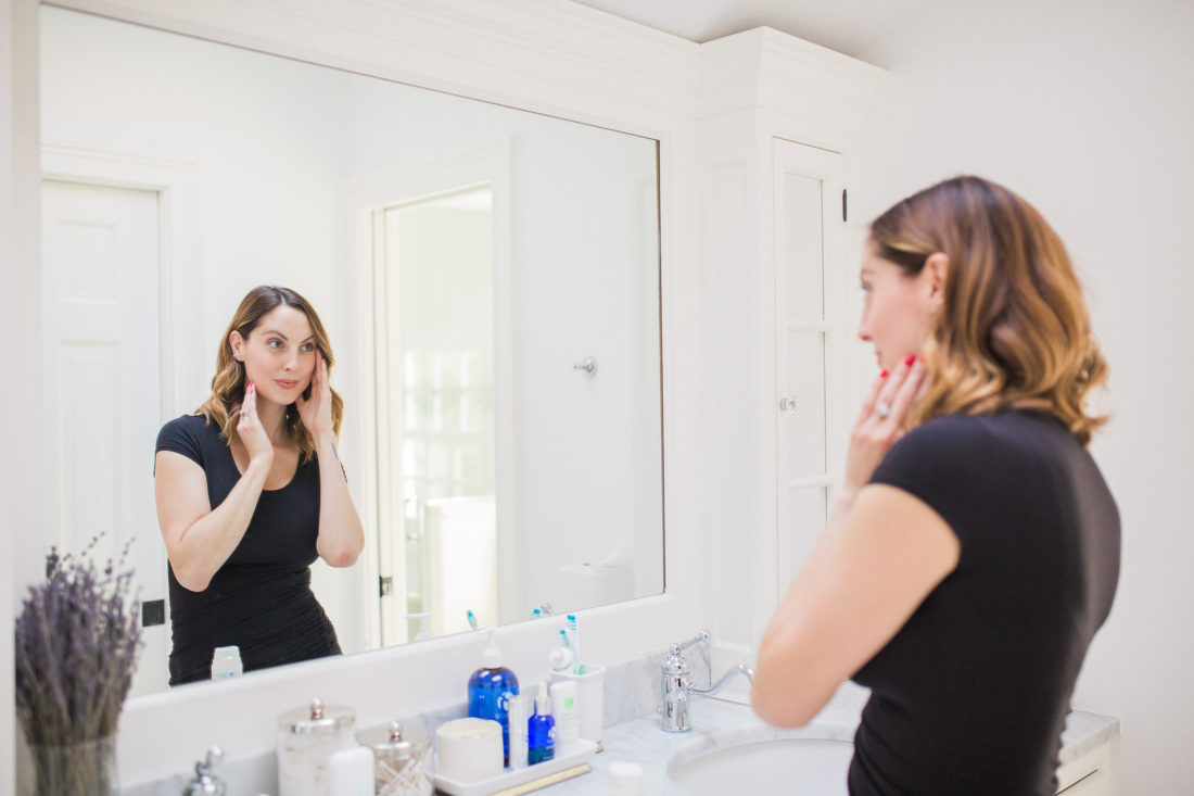 Eva Amurri Martino of lifestyle and motherhood blog Happily Eva After applying face cream in the master bathroom of her connecticut home