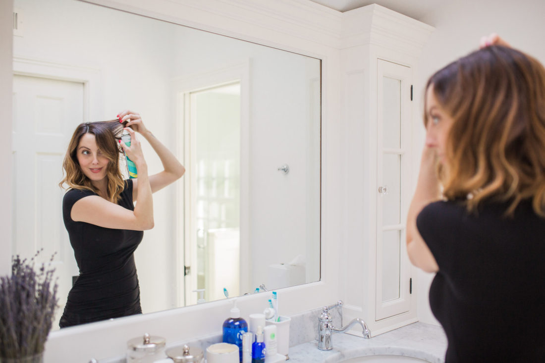 Eva Amurri Martino of lifestyle and motherhood blog Happily Eva After applying dry shampoo to her hair in the master bathroom of her Connecticut home