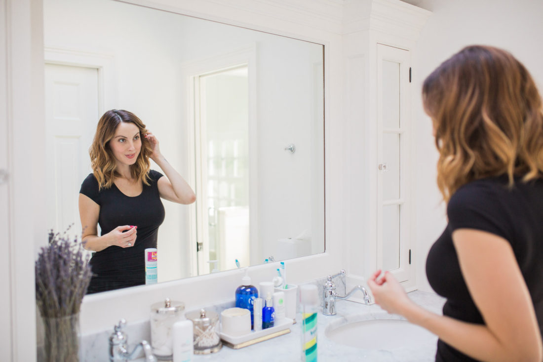 Eva Amurri Martino of lifestyle and motherhood blog Happily Eva After fixing her hair in the master bathroom of her connecticut home