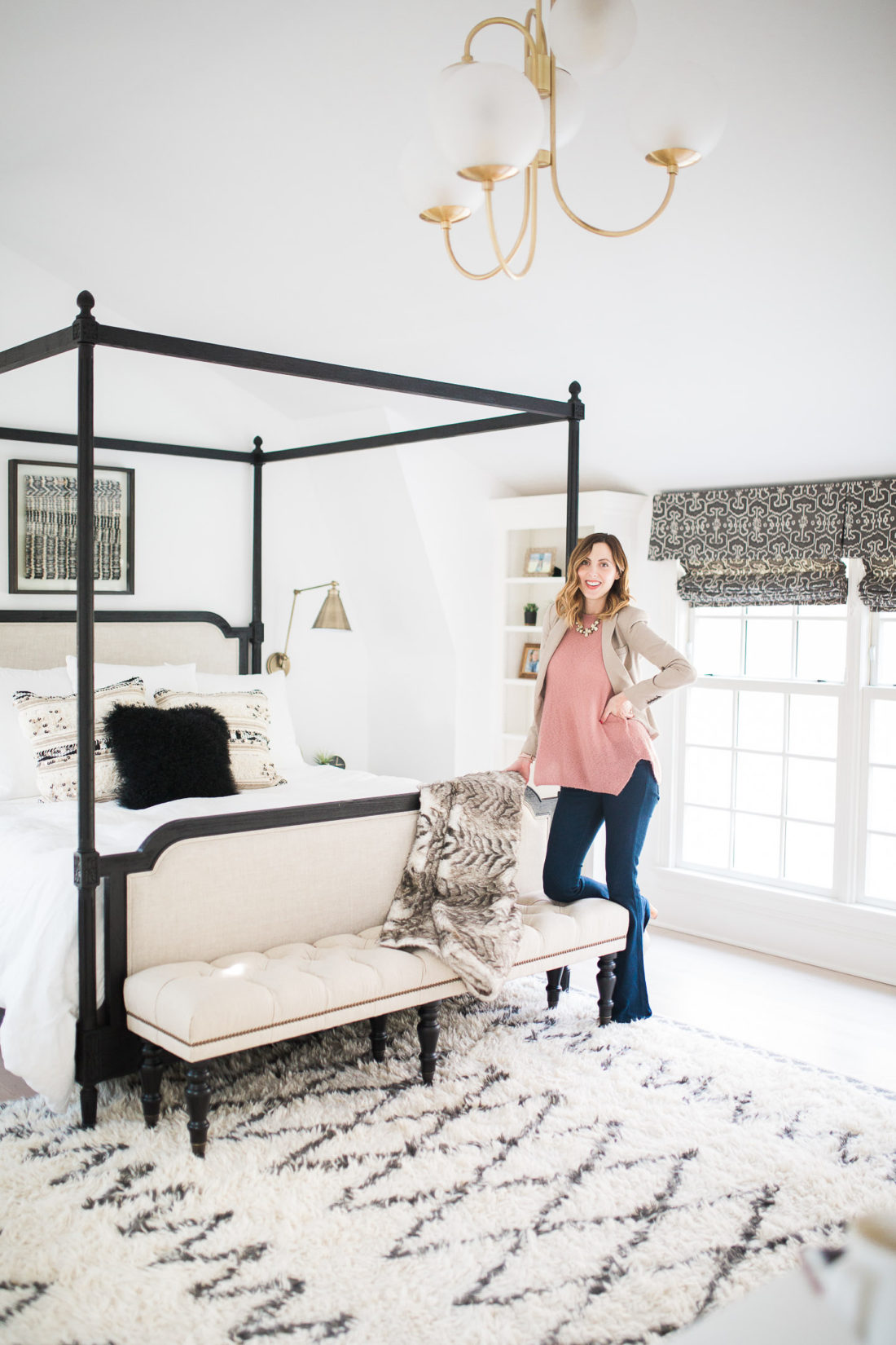 Eva Amurri Martino of lifestyle and motherhood blog Happily Eva After poses in her black, white, and brass master bedroom in Connecticut