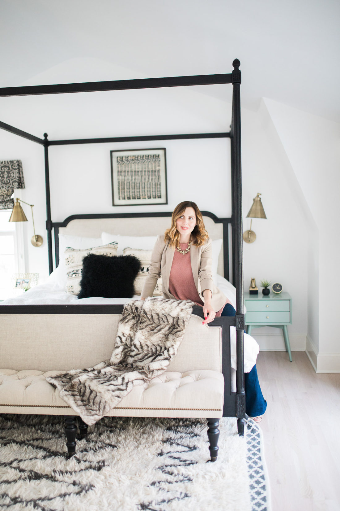 Eva Amurri Martino of lifestyle and motherhood blog Happily Eva After poses in her black, white, and brass master bedroom in Connecticut