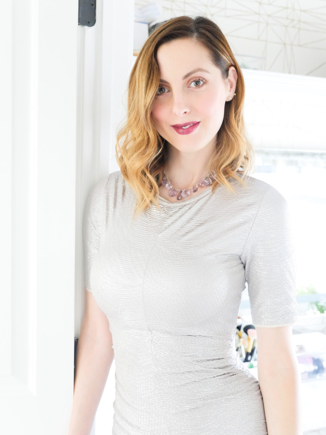 Eva Amurri Martino wears a silver bodycon dress and a vintage necklace with purple stones with a dark purple lipstick