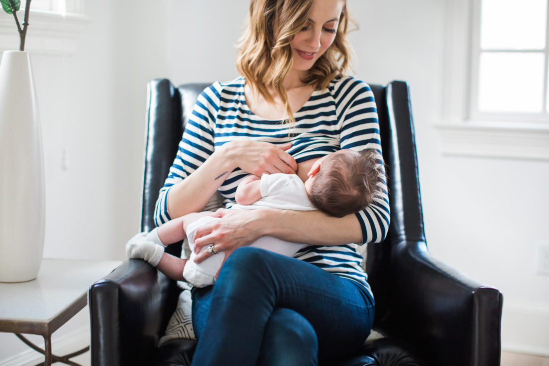 Eva Amurri Martino of lifestyle and motherhood blog Happily Eva After breastfeeds her newborn son Major while wearing a striped breastfeeding shirt