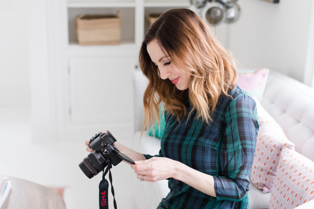 Eva Amurri Martino wears a plaid shift dress and black boots while she shoots with her camera in her studio in Connecticut.