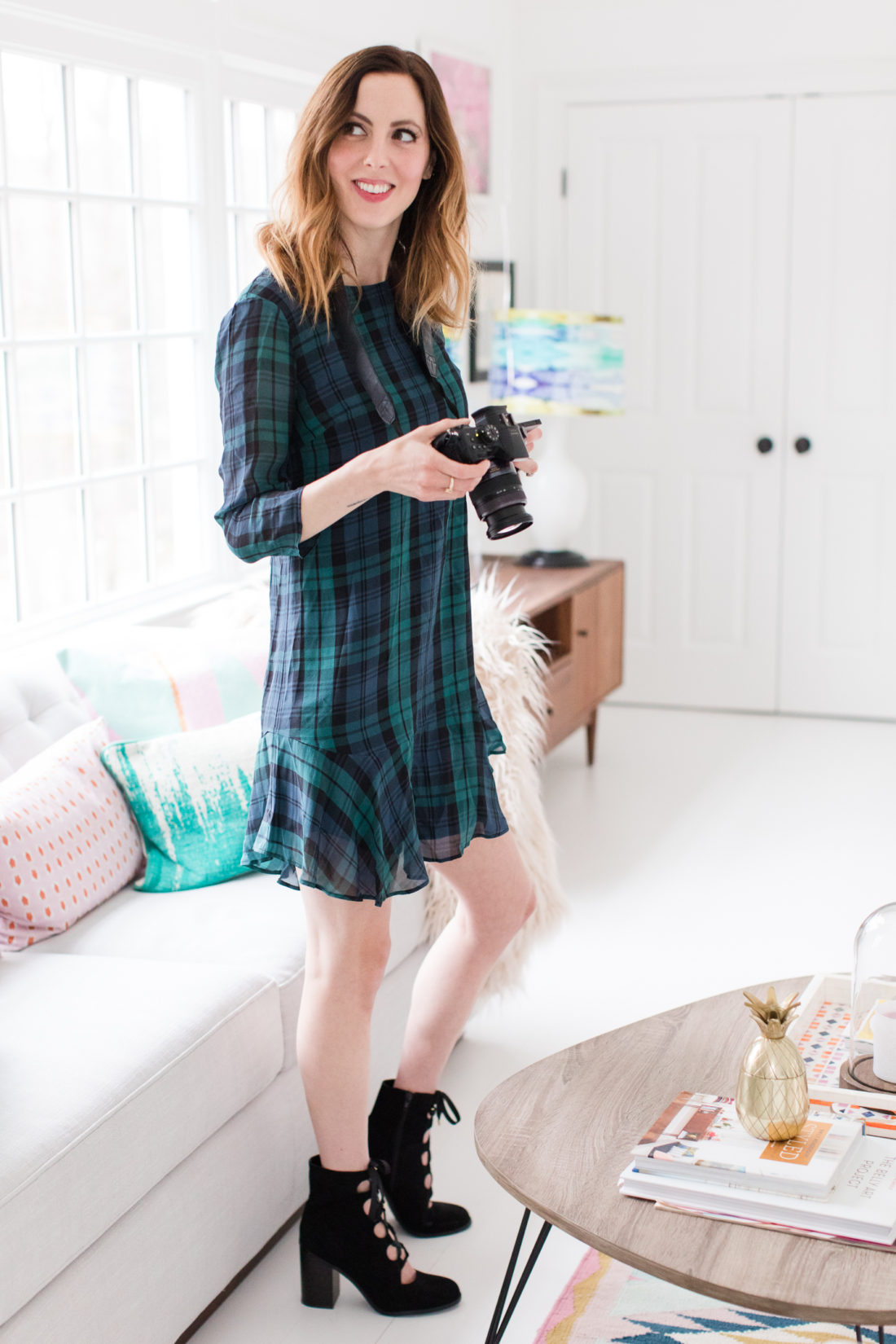 Eva Amurri Martino wears a plaid shift dress and black boots while she shoots with her camera in her studio in Connecticut.