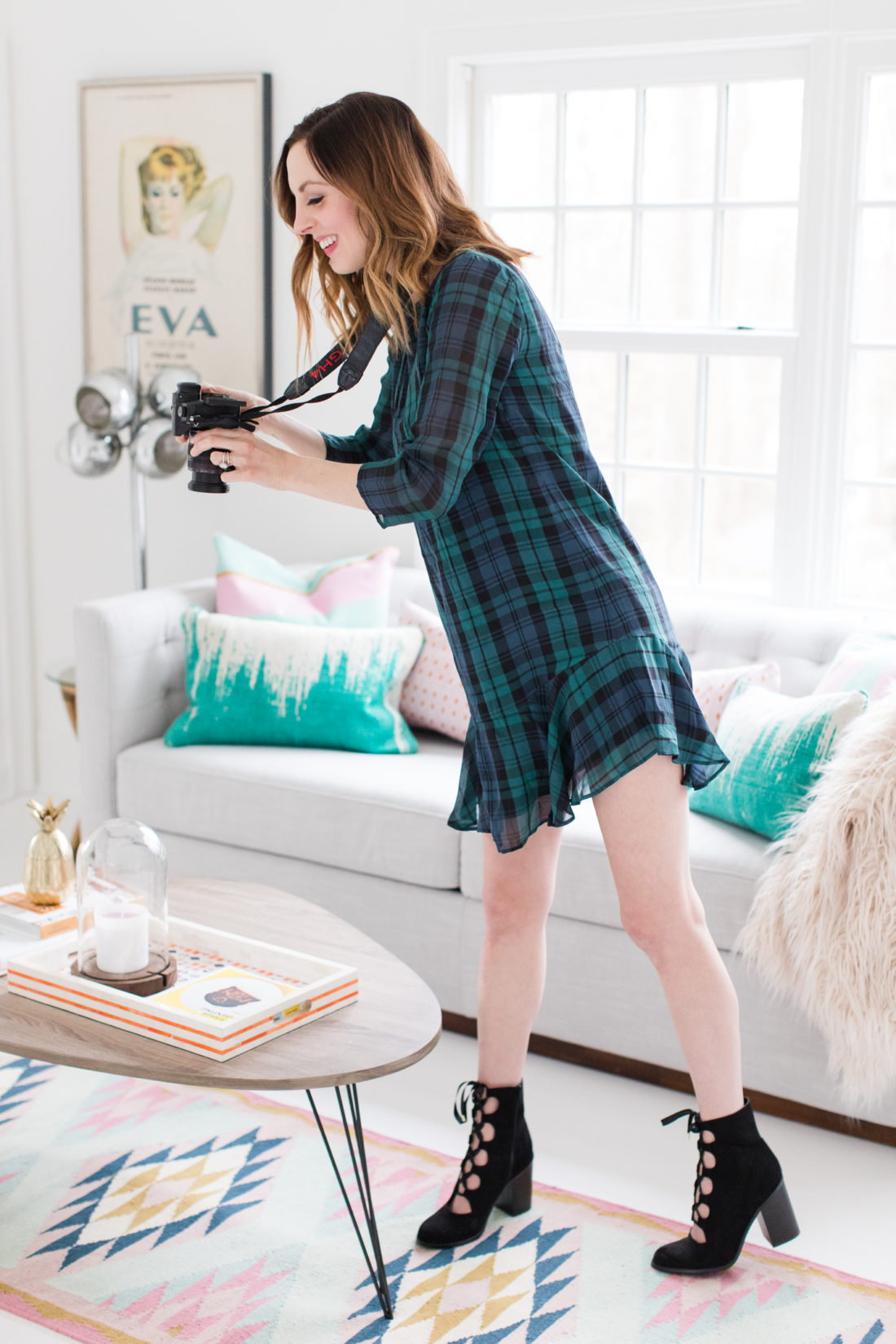 Eva Amurri Martino wears a plaid shift dress and black boots while she shoots with her camera in her studio in Connecticut.
