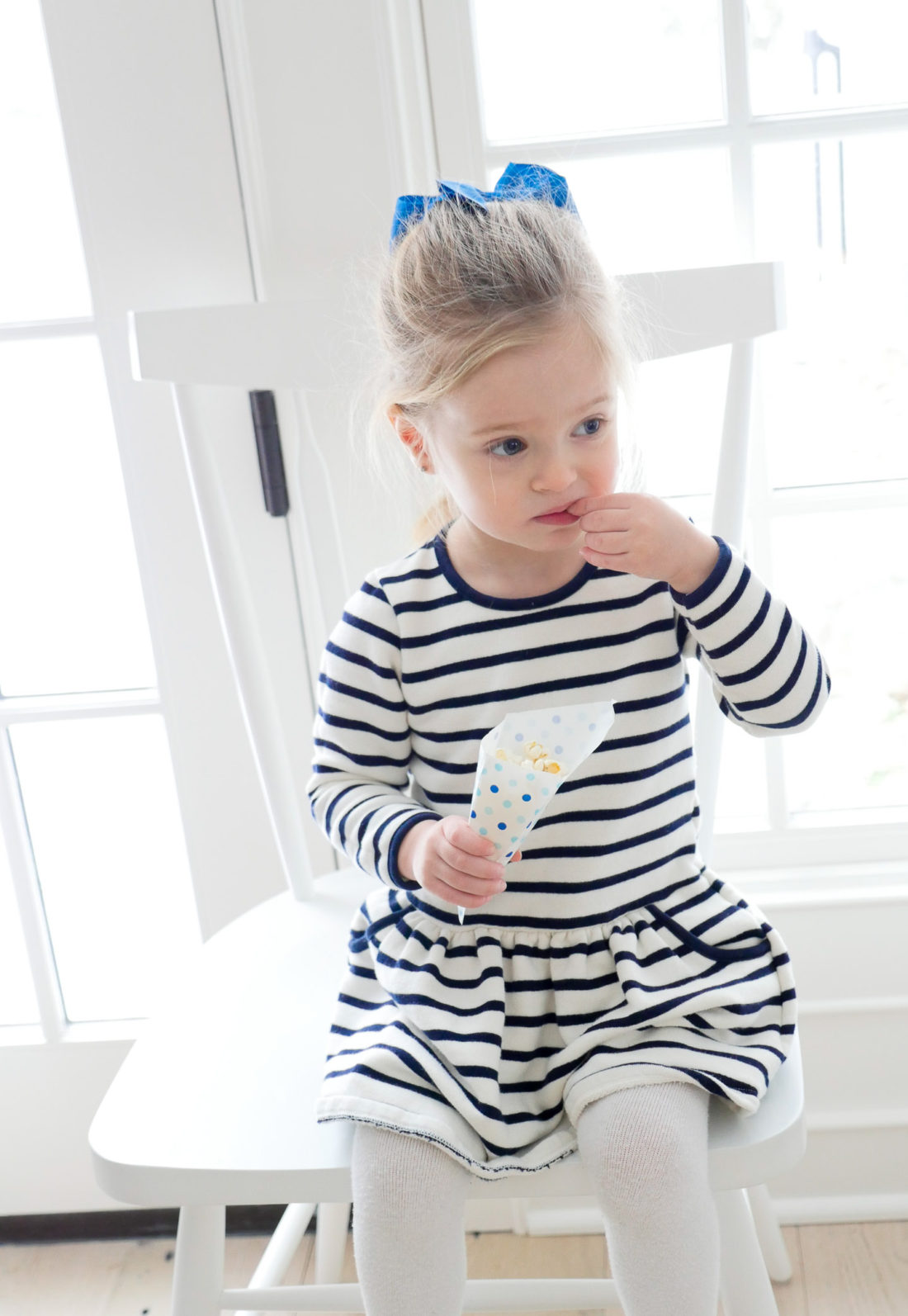 Marlowe Martino wears a striped nautical dress and munches from a cone of popcorn