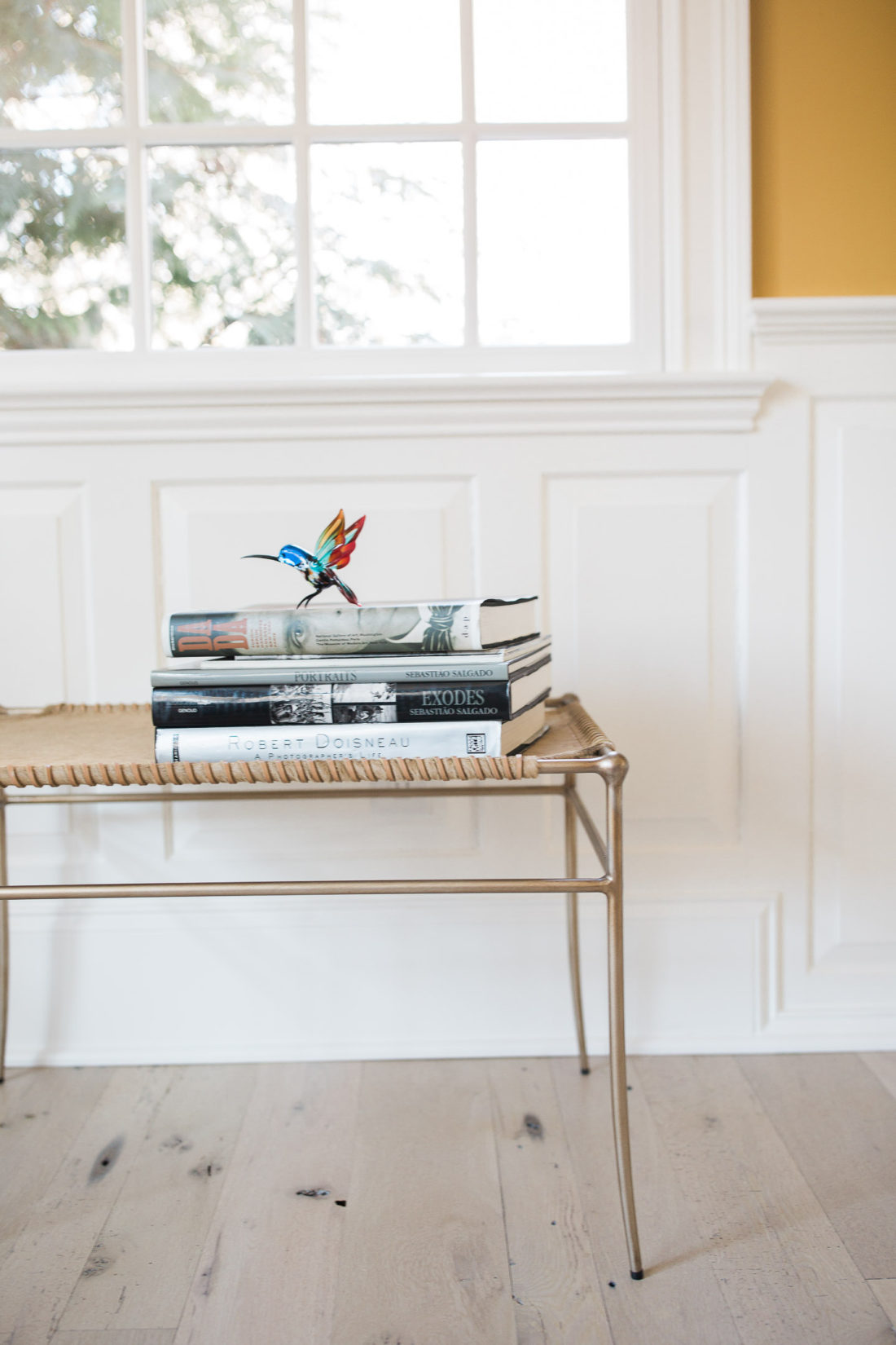 a bench with some books on display sits underneath the window of the living room at Eva Amurri Martino's Connecticut home