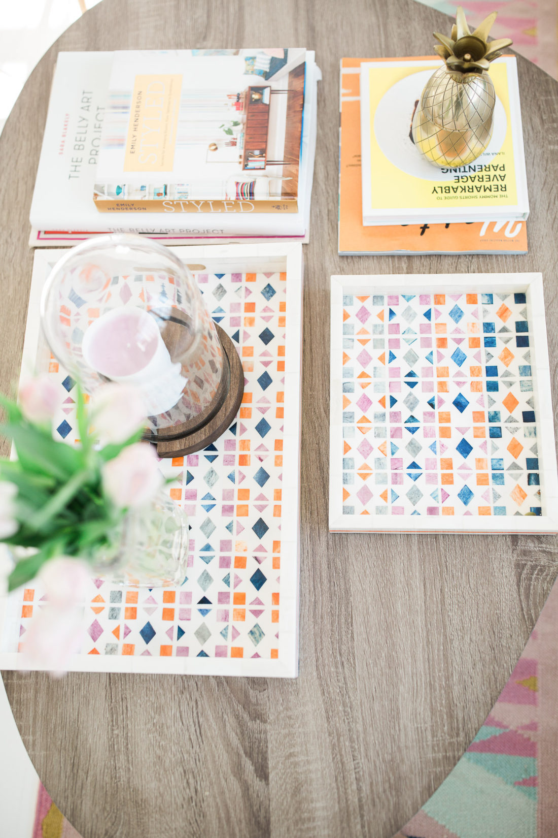 Multicolored decorative trays and stacks of books adorn the coffee table in the Happily Eva After studio