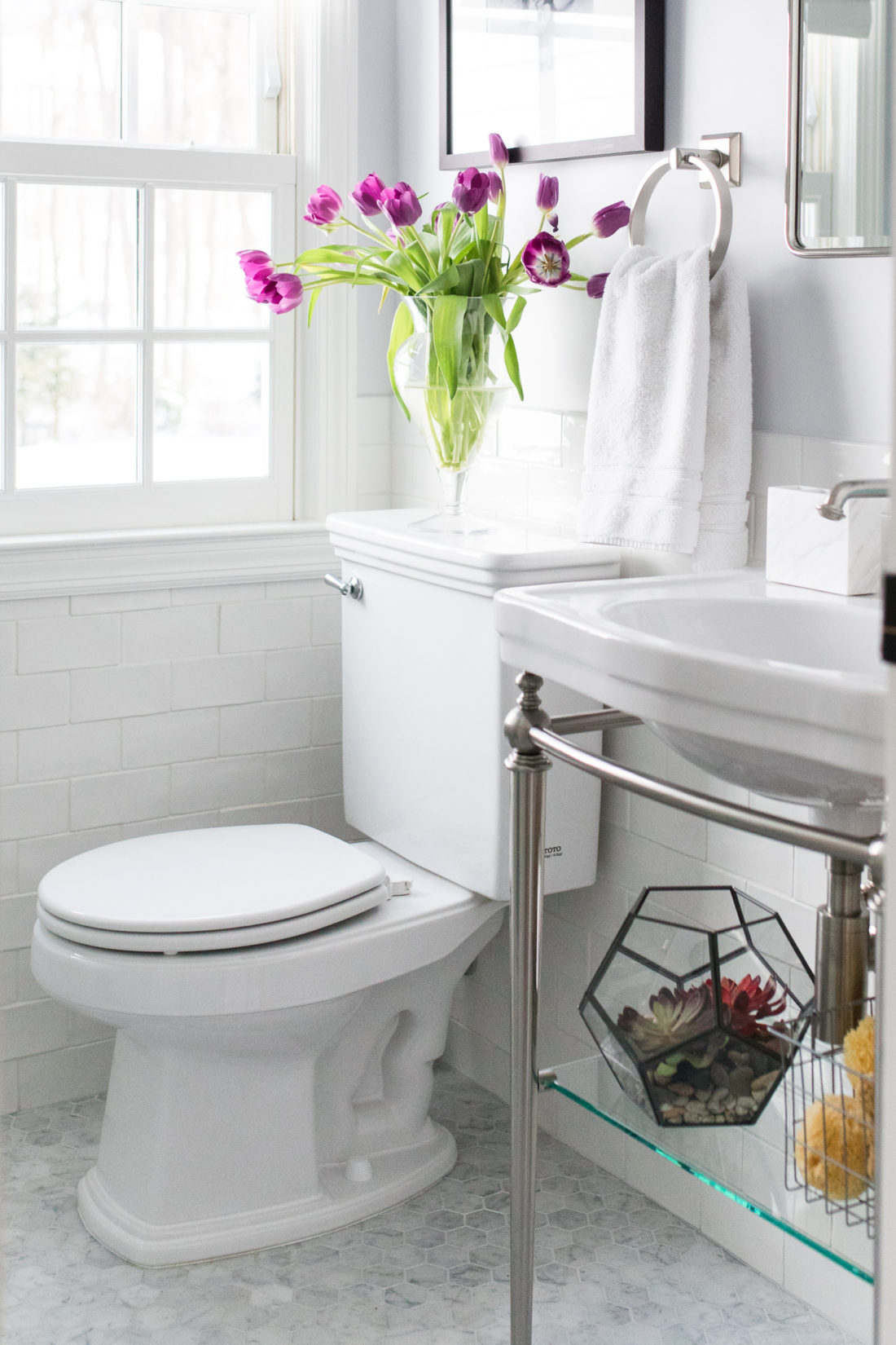 The bright white and chrome bathroom in Eva Amurri Martino's connecticut home, featuring irregular subway tile and marble hexagonal floor tiles