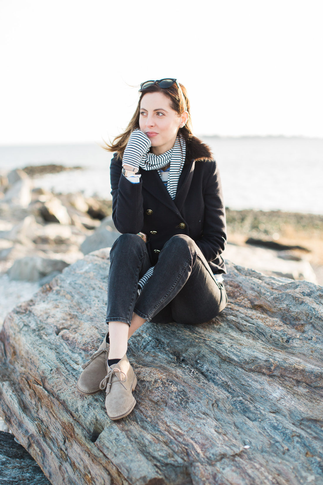 Eva Amurri Martino sits on a boulder on the beach in Connecticut with the long island sound behind her