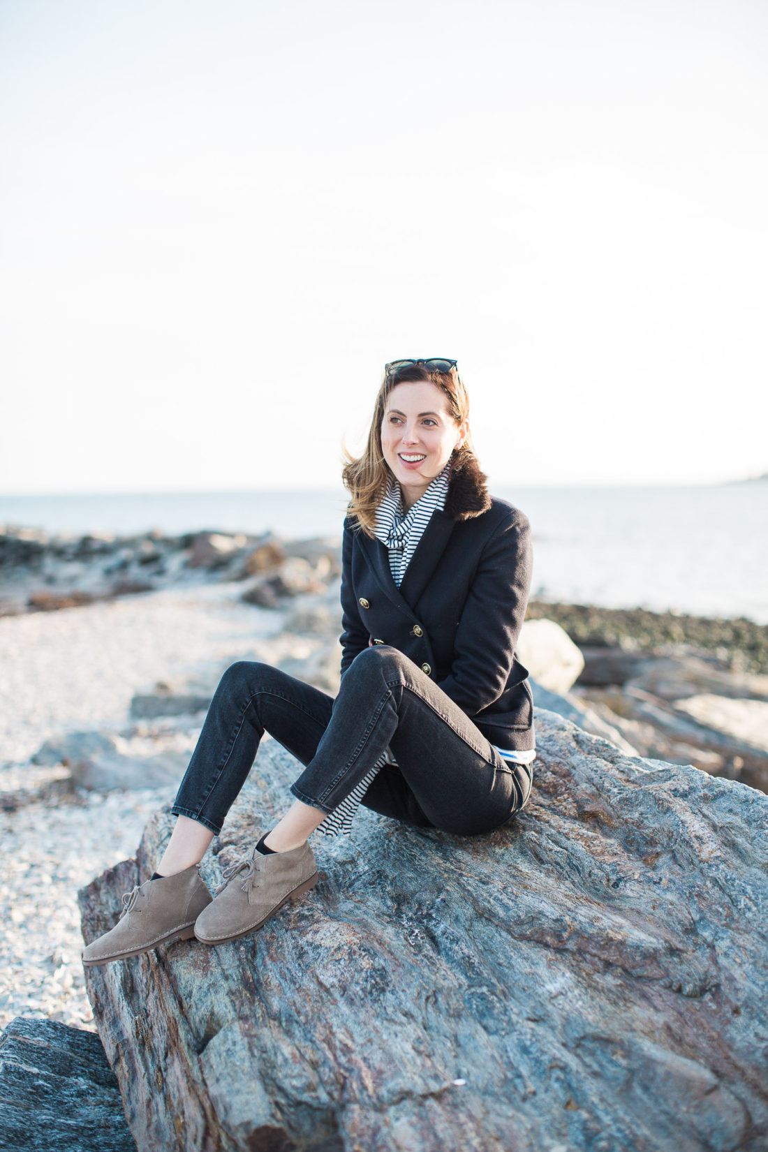 Eva Amurri Martino sits on the rocks at Compo Beach wearing a navy blue peacoat and striped scarf