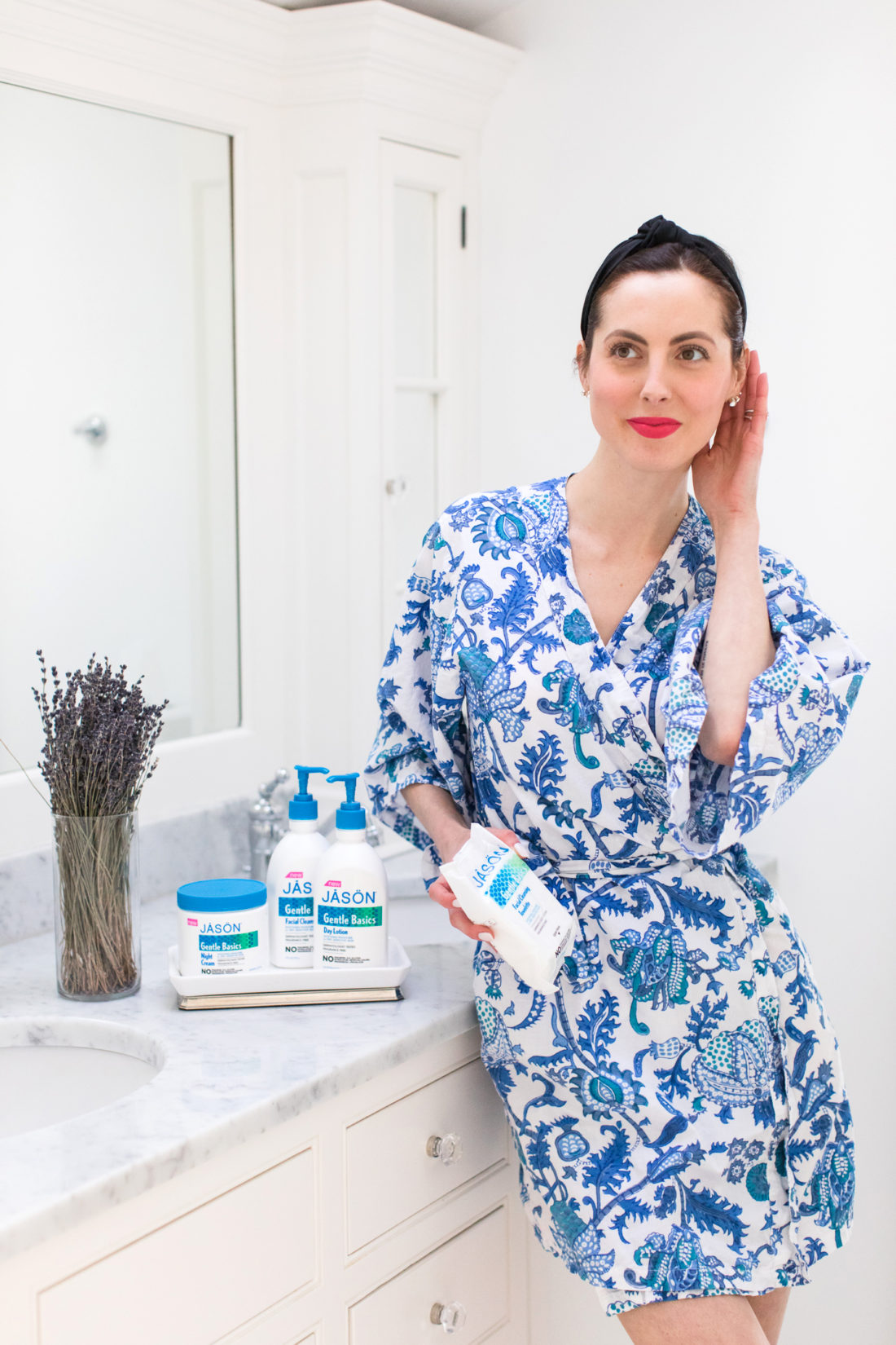 Eva Amurri Martino stands in her master bathroom in a blue patterned summer robe and pink lipstick preparing to wash off her daily makeup