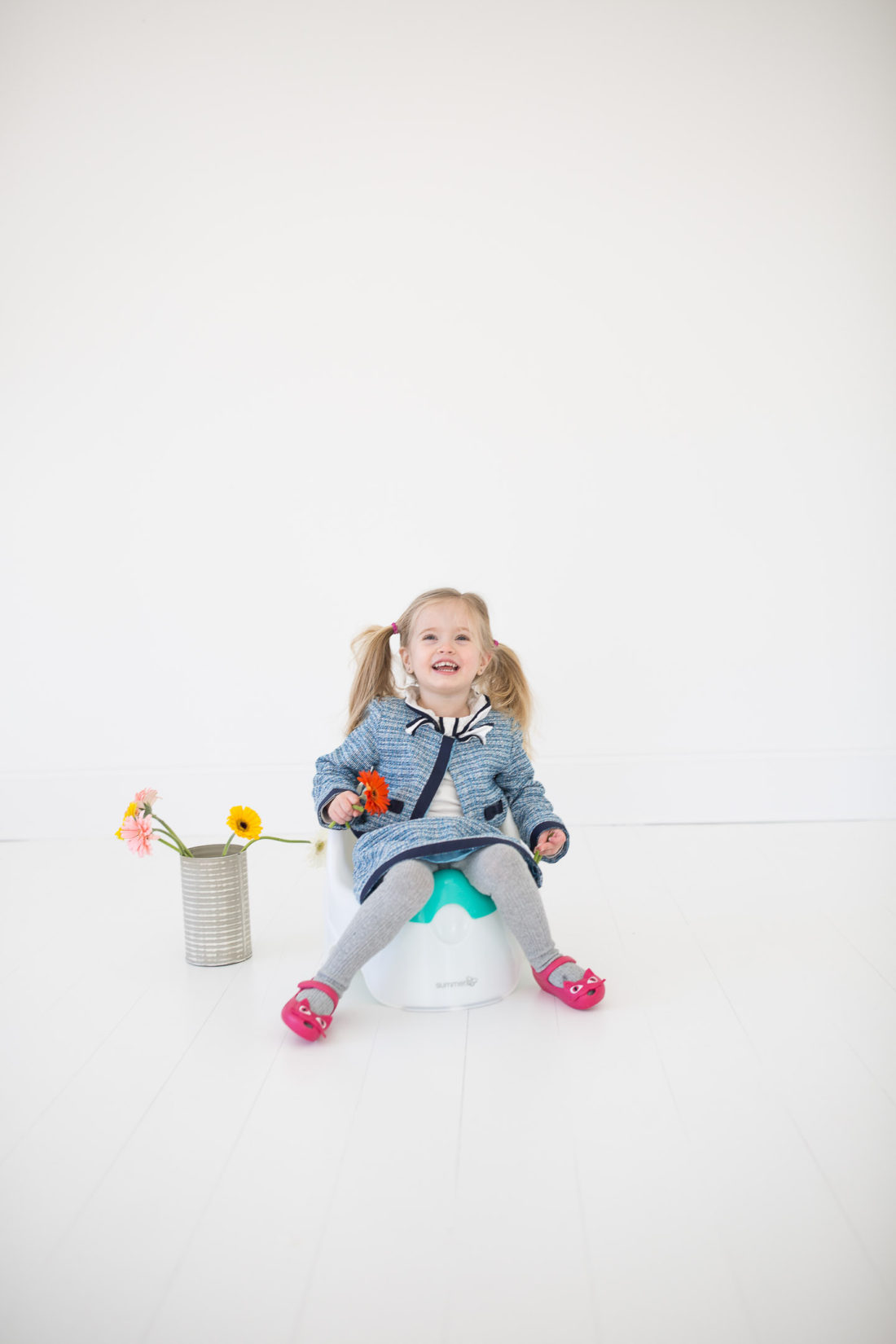 Marlowe Martino wears a tweed suit and sits on the toddler potty holding a flower in her hand