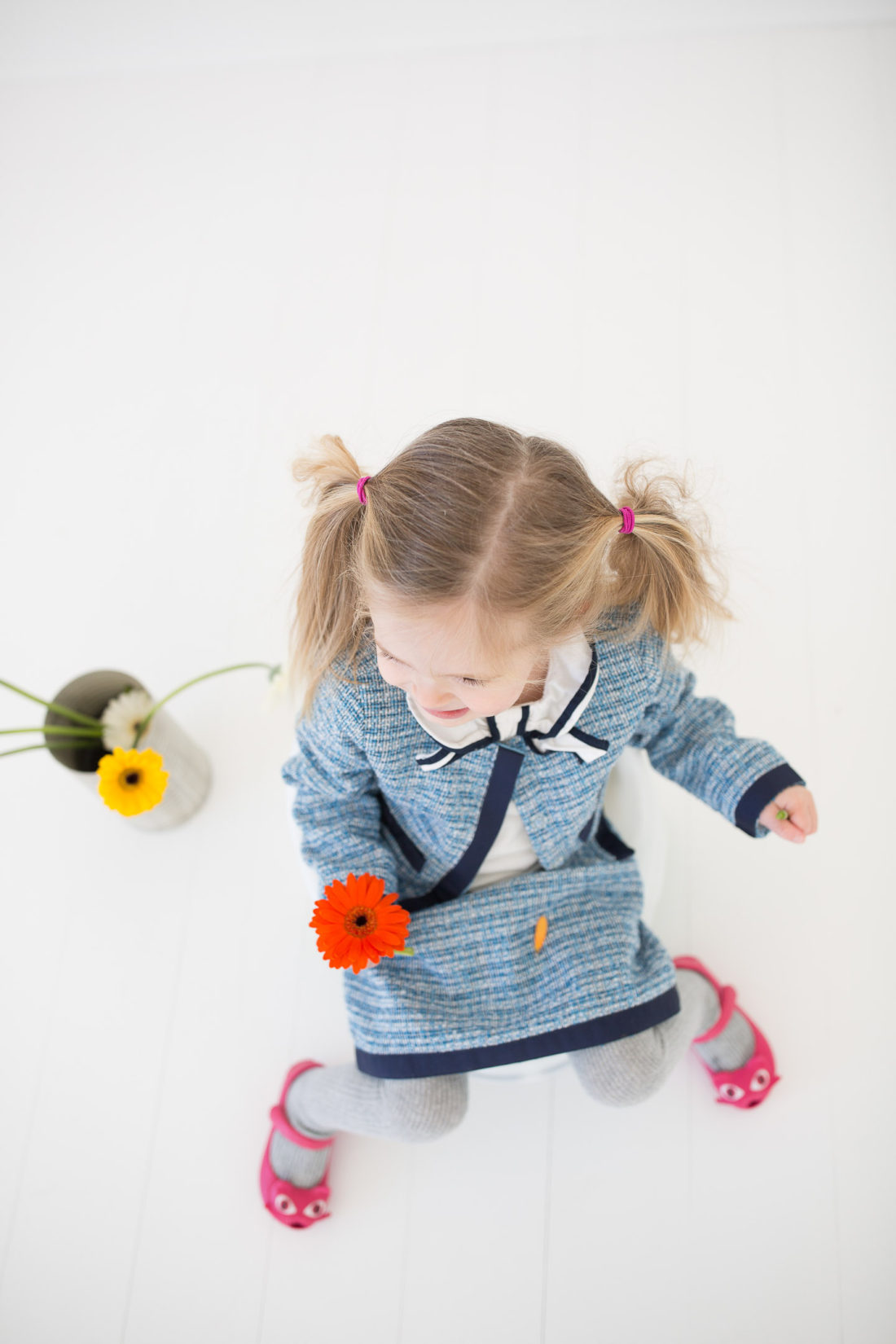 Marlowe Martino wears a tweed suit and sits on the toddler potty holding a flower in her hand