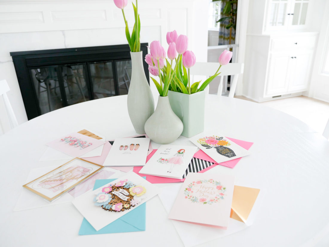 Eva Amurri Martino's white kitchen table is decorated with a trio of vases filled with pink tulips, and an array of mother's day greeting cards