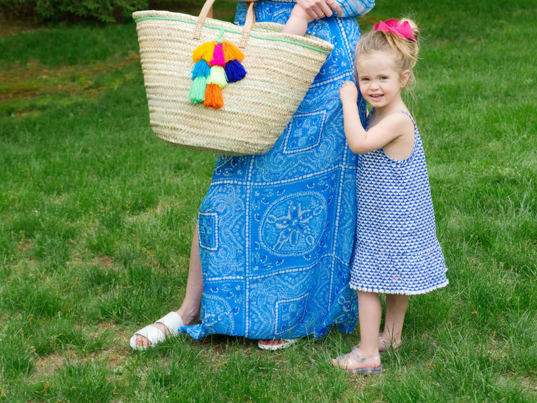 Marlowe Martino wears a blue and white patterned dress and clings to her mother's leg