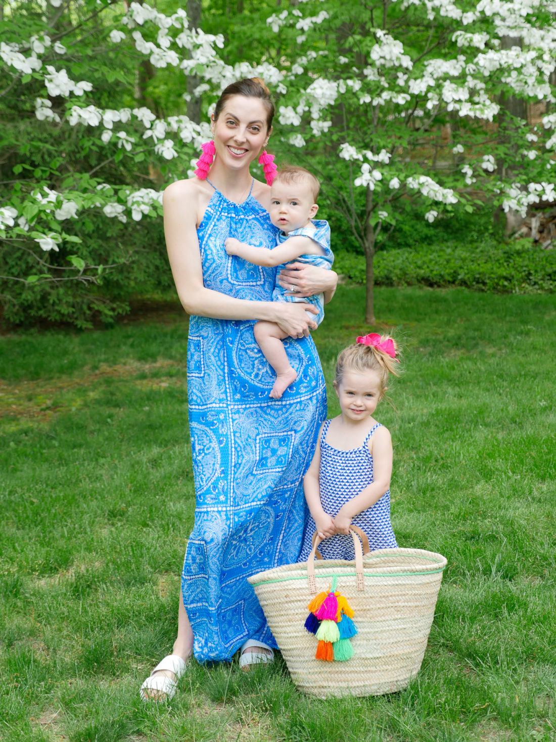 Eva Amurri Martino stands with her children in the countryside wearing a blue maxi dress and magenta tassel earrings