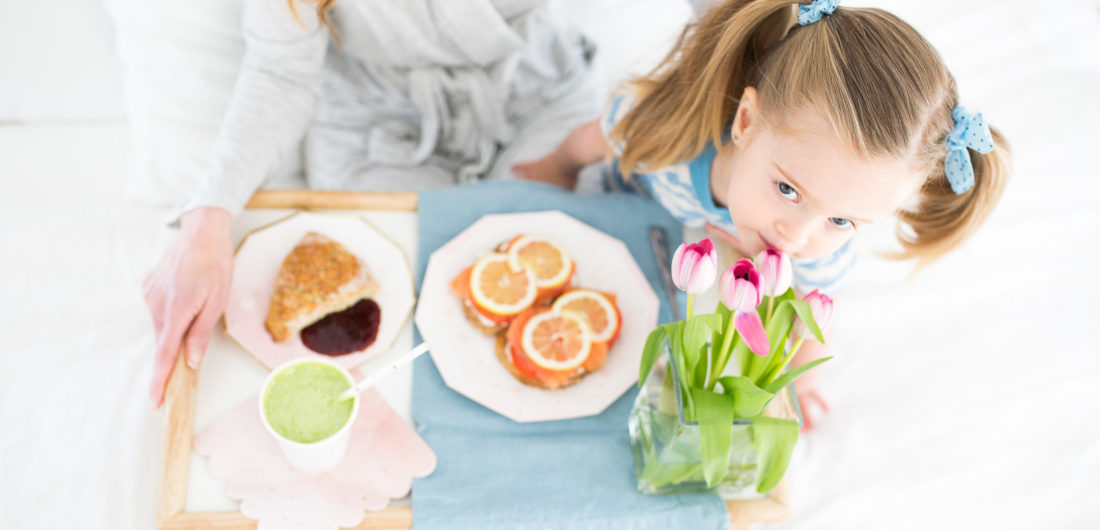 Marlowe Martino smells a bouquete of flowers on a mother's day breakfast tray