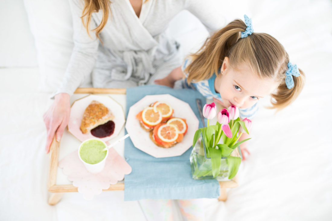 Marlowe Martino smells a bouquete of flowers on a mother's day breakfast tray