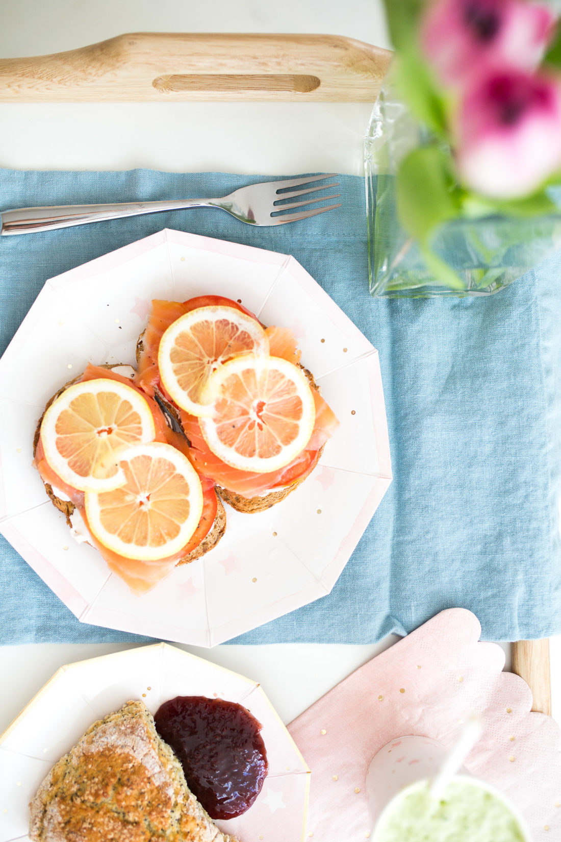 Smoked salmon toast, freshly baked lemon poppyseed scones, and a green smoothie sit on a breakfast tray