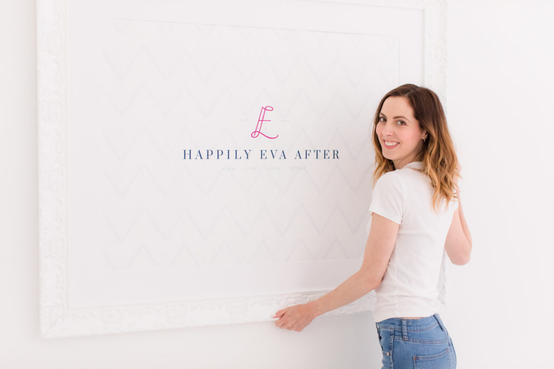 Eva Amurri Martino hangs up a framed poster of the Happily Eva After logo on her studio wall