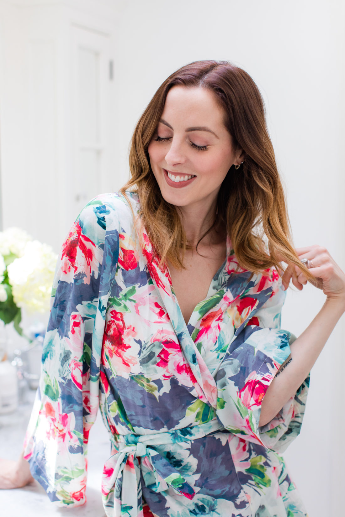 Eva Amurri Martino wears a floral robe and runs her hands through her smooth bouncy blow out