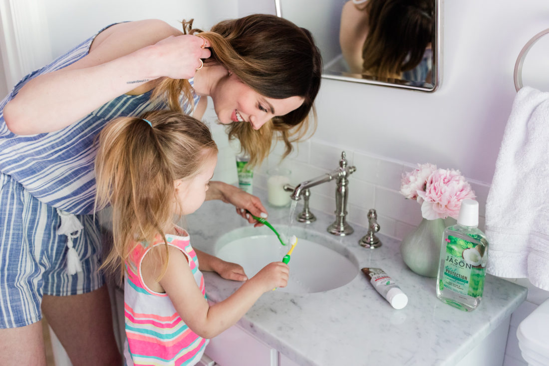 Eva Amurri Martino wears a blue and white striped romper and brushes her teeth with two year old daughter, Marlowe, in the bathroom of their Connecticut home