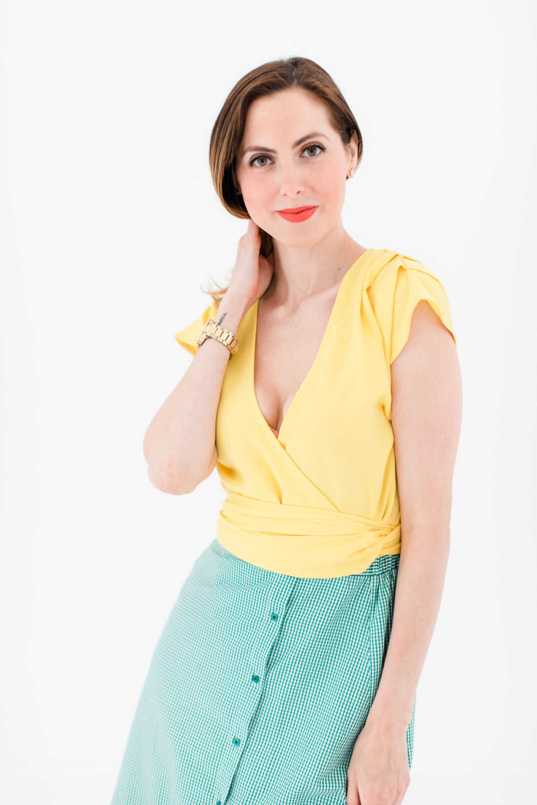 Eva Amurri Martino wears a bright yellow wrap top and gingham ruffle skirt as part of a post about packing for a trip